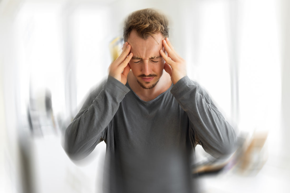 man gripping the sides of his head due to experiencing a strong headache