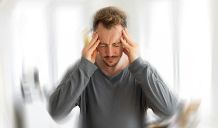 man gripping the sides of his head due to experiencing a strong headache